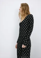 Vestido largo negro con estampado de lunares blancos, de corte recto, escote redondo y mangas largas.