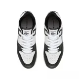 Championes Lacoste modelo Courtcage, de diseño urbano y deportivo. Presentan una combinación de paneles en color blanco y negro, con el icónico logo del cocodrilo bordado en el lateral. Cuentan con cierre de cordones y suela de goma resistente.