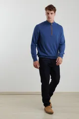 Sweater de punto gris con medio cierre frontal, cuello alto y coderas en tono marrón. Presenta un diseño clásico con puños y ruedo acanalados.
