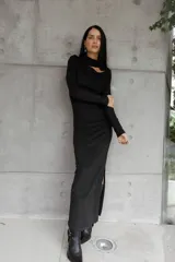 Vestido negro de largo midi, confeccionado en tejido grueso con efecto ante. Presenta mangas largas, escote con abertura en el pecho, cintura elastizada con frunces, tajo lateral y cuello medio alto.