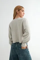Sweater de punto negro, de corte holgado y diseño cropped, con cuello redondo y mangas largas.