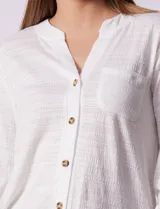 Blusa Ninety color beige con textura, cuello base con escote en V y abertura central con botones. Tiene un bolsillo en el pecho y mangas 3/4 regulables con presilla y botón.