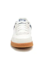 Sneaker Caterpillar modelo Pause Retro, de diseño minimalista con exterior en lona blanca y detalles en gamuza. Presenta suela de goma color caramelo con textura de panal y logo de la marca en el lateral y la lengüeta.