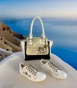Cartera de cuero hecha a mano de la marca Carolina De Cunto, modelo Mila, con diseño tricolor en blanco, negro y detalle central dorado texturizado con arte pintado a mano. Cuenta con asas superiores blancas y herrajes metálicos.