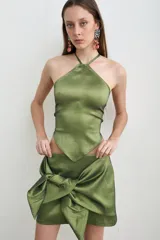Falda corta verde oliva confeccionada en tafeta, con diseño cruzado y un gran moño anudado en el frente.