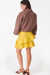 Minifalda amarilla confeccionada en lino italiano, de corte en A, con diseño de doble volado escalonado y detalles de terminación con bordado calado.