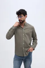 Camisa de lino y algodón color celeste, con cuello mao, cierre frontal de botones claros y pequeño bordado de pato en el pecho.