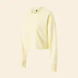 Buzo deportivo de corte crop, color amarillo pastel, con cuello redondo, mangas largas con puños acanalados y abertura para el pulgar.