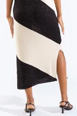 Vestido midi tejido bicolor en negro y beige con brillo sutil, escote bote, diseño sin mangas y abertura lateral en el dobladillo.