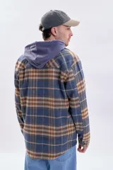 Sobrecamisa de franela a cuadros en tonos azul marino y marrón, con cierre frontal de botones, cuello camisero y bolsillos frontales con solapa.