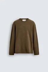 Jersey de punto de lana con corte regular fit, cuello redondo y manga larga. Presenta un diseño minimalista con acabados enrollados en cuello, puños y ruedo.