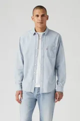 Camisa celeste a rayas verticales blancas, de corte recto, manga larga y bolsillo en el pecho.
