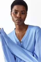 Saco corto de punto fino en mezcla de viscosa color celeste, con cuello en V, cierre frontal de botones y diseño entallado con detalles acanalados en los puños y el bajo.