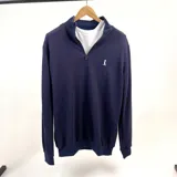 Buzo azul marino de algodón de punto con medio cierre y cuello alto. Presenta un logo pequeño bordado en el pecho.