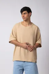 Remera de corte oversize confeccionada en tejido texturado tipo lino, de color beige, con cuello redondo amplio y mangas cortas de calce relajado.