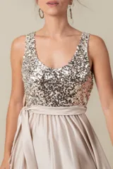Vestido largo rojo con cuerpo de lentejuelas y falda de satén con caída fluida. Presenta escote redondo, sin mangas y un lazo en la cintura.
