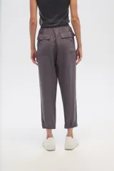 Pantalon de corte relajado, color gris, con cintura elástica y cordón ajustable. Presenta bolsillos frontales tipo parche y puños elásticos en los tobillos.