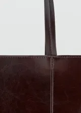 Bolso tipo tote de poliuretano en color bordó, con efecto craquelado, asas largas para el hombro y costuras verticales decorativas en el frente.