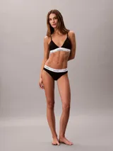 Bombacha clásica tipo bikini de Calvin Klein, color negro, confeccionada en mezcla de algodón, modal y elastano. Presenta una pretina elástica distintiva con el logo de la marca en contraste y ofrece cobertura total en la espalda.