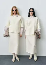 Jersey de punto fino color crema, con diseño oversize, cuello redondo y mangas cortas.