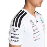 Remera deportiva Adidas del equipo Mercedes AMG Petronas, color blanco con detalles en negro y turquesa. Incorpora múltiples logotipos de patrocinadores impresos en el frente y las mangas, cuello en V y las clásicas tres tiras de Adidas en los hombros.