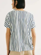 Blusa de manga corta con cuello redondo y estampado de cuadrícula blanca sobre fondo color tostado.