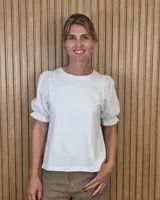 Remera blanca con cuerpo de algodón y mangas cortas abullonadas de broderie, con cuello redondo.