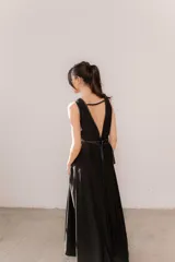 Vestido largo negro, con escote en V profundo ribeteado en ecuero y doble cinto del mismo material que marca la cintura. Cuenta con falda amplia con gran caída y aberturas laterales.