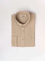 Camisa de manga larga color beige, confeccionada en lino y poliéster, con cuello abotonado y bolsillo en el pecho.