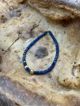 Collar corto de cuentas facetadas color azul con detalles de cuentas doradas.