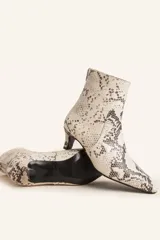 Botín blanco con estampado de piel de serpiente, punta fina y taco chupete. Cierre con cremallera en la parte trasera.