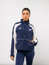Campera deportiva Umbro del Club Nacional de Football, con diseño de bloques de color en azul marino y blanco. Presenta cuello alto, cierre frontal completo, bolsillos laterales y el escudo del club junto al logo de la marca en el pecho.