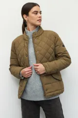 Campera capitoneada color beige, de cuello alto, con bolsillos de solapa y botones metálicos.