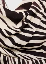 Blusa sin mangas con estampado de cebra en tonos marrón y beige. Tiene cuello asimétrico, diseño drapeado y corte entallado.