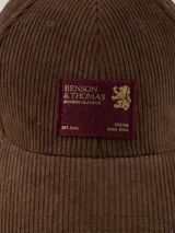 Gorra de béisbol de pana azul marino con parche lateral con el logo de la marca Benson & Thomas.