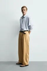 Pantalón chino straight fit de corte recto y holgado, color tostado, con pliegues frontales en la cintura, bolsillos laterales y cierre con cremallera y botón.
