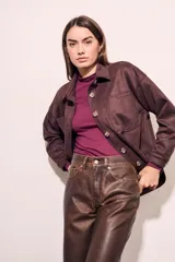 Sobrecamisa de gamuza sintética en color marrón chocolate, con corte oversize, cuello camisero, cierre frontal con botones y bolsillos frontales tipo parche.