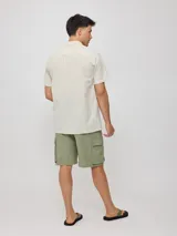 Camisa de manga corta con diseño a rayas verticales finas, cuello clásico y cierre frontal con botones.