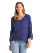 Blusa azul de escote en V y manga larga con terminación amplia. Presenta detalles de bordado y calados tanto en las mangas como en el ruedo delantero.