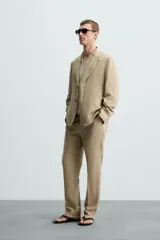 Blazer color beige de corte relaxed fit, confeccionada en tejido con viscosa. Tiene cuello con solapas de muesca, manga larga con puño abotonado, bolsillos frontales de plastrón, medio forro interior, aberturas en la espalda y cierre frontal con botones. Presenta un efecto lavado.