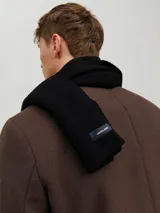 Bufanda de punto color negro, con diseño liso y etiqueta pequeña de la marca en el extremo.
