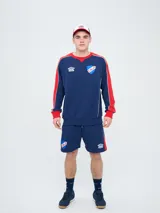 Buzo deportivo azul marino con detalles en rojo y blanco en cuello, hombros y mangas, de cuello redondo y manga larga, con el logo de Umbro y el escudo del Club Nacional de Football bordados en el pecho.