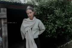 Campera de punto color beige, con cierre frontal, cuello alto y diseño de líneas verticales. Incluye una bufanda a juego del mismo tejido.