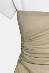 Top de escote asimétrico y manga corta, color blanco con fajín superpuesto a contraste en tono beige y detalles de frunces laterales.