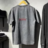 Remera oversize de algodón con efecto stone wash en color gris, manga corta y cuello redondo. Presenta un pequeño bordado en hilo rojo en la parte posterior con la palabra "Become.".