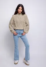 Sweater beige de punto trenzado con cuello alto, mangas largas abullonadas y detalle de flecos en el frente.