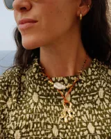 Collar con dije de bronce macizo con forma orgánica irregular, similar a un coral, suspendido de un cordón negro de seda natural anudado.