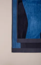 Toalla de algodón color azul con detalle de franja naranja con el nombre de la marca.