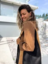 Sobre camisa de gamuza con diseño de paneles verticales en colores marrón, tostado y negro. Presenta cuello clásico, cierre frontal con botones metálicos y un bolsillo en el pecho con solapa.