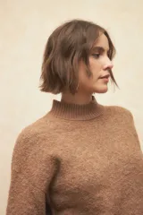 Polera beige de tejido de punto con cuello alto y mangas largas.